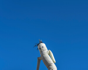 A grey waving inflatable tube guy moves agains a clear blue sky.