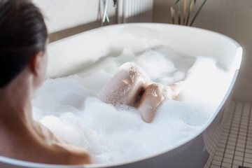 Fototapeta premium Woman taking a bath with hot water and bubbles