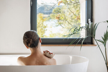 Woman taking hot bath in hotel, looking at window