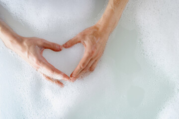 Woman taking bath with bubble water, making heart shape