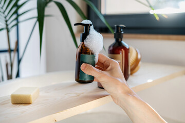 Woman taking brown recycled glass bottle with soap dispenser