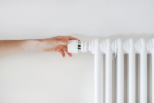 Woman Hand Turning Regulator Knob On Heating Radiator In Room