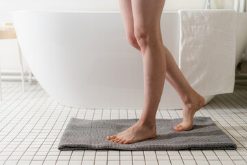 Young woman with perfect smooth legs standing on shower mat - obrazy, fototapety, plakaty