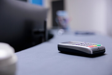 Bank terminal on desk in cashier area of medical institution. Technological gadget to receive payments from patients on counter in medical clinic. Bank card payment collection tool in hospital.