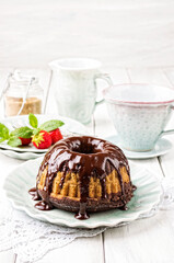 Traditional marble cake gugelhupf with chocolate icing and a strawberry served as close-up on a design plate