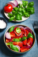 Bright healthy salad with tomatoes, basil and blue onions.