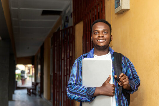 young African black teen boy with backpack holding notebook laptop