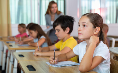 Schoolgirl sitting in classroom during lesson in elementary school. High quality photo