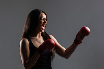 beautiful girl exercising karate punch and screaming against gray background
