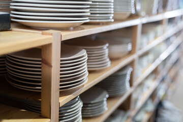 Showcase with various new plates stacked on shelves in dishware department of supermarket