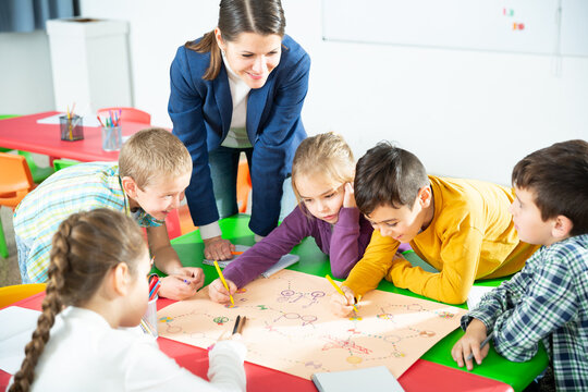 Teacher and collective of elementary age children draw together a board game. High quality photo