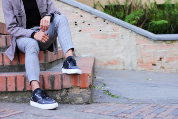 legs of a young man sitting on stairs in a casual manner
