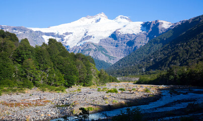 Naklejka na ściany i meble Cauquenes River bank and view of mountain (volcano) Tronador and glacier on sunny day. Andes, Patagonia, Argentina