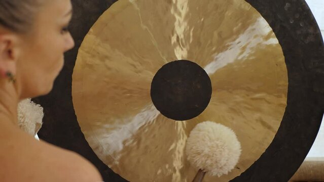 Gong and gong mallets, close up. Woman taps the gong with soft hammers