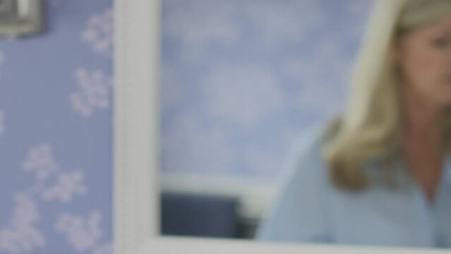 Close up of menopausal mature woman taking vitamins or medication in mirror at home - shot in slow motion
