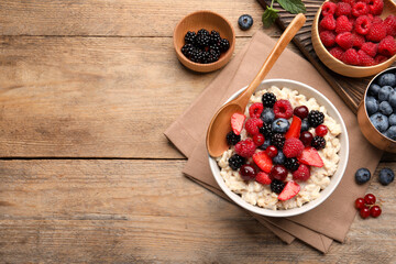 Flat lay composition with tasty oatmeal porridge and ingredients served on wooden table. Space for text