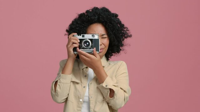 Portrait of cheerful beautiful black female with Afro Hairstyle in good mood with camera standing in studio. Happy pretty young African American woman tourist taking photo.Photographer taking pictures