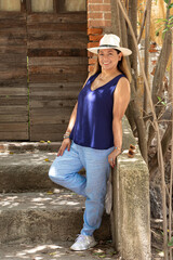 Latina morena con sombrero y posando en el pueblo