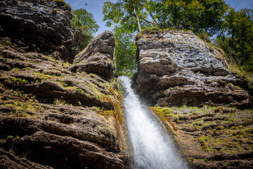 Pericnik waterfall with water falling  down a mountain, seen from below, with a blue sky in summer. Slap Pericnik falls are a waterfall of Slovenia, in Mojstrana, in the triglav national park.....
