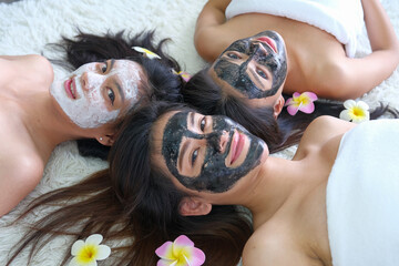 Closeup group of young asian women looking and smiling camera with facial masks over white capet background