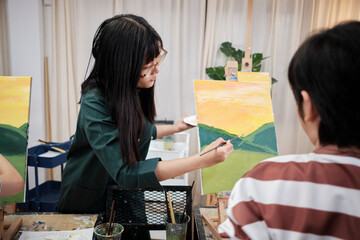 A female Asian teacher teaches and demonstrates to the children on acrylic color picture painting...