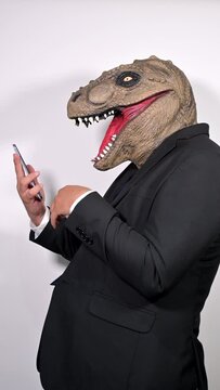Angry businessman with t rex mask talking to his boss on the phone