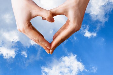 Fototapeta premium Human hands in the form of heart against the sky. Hands in shape of love heart. Love, friendship concept.