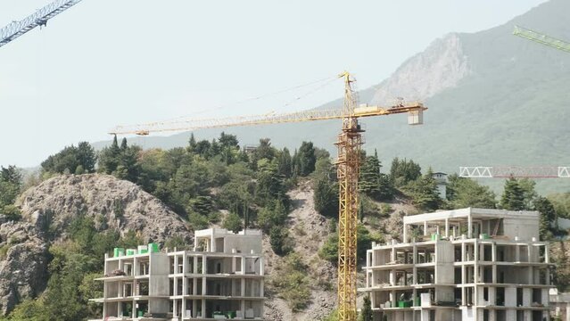 Close-up Construction cranes with new buildings under construction against the backdrop of a mountain. Construction. Development of building architecture. nature landscape background
