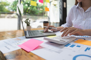 accounting concept. businesswoman working using calculator with money stack in office