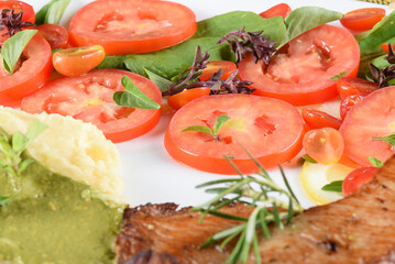 delicious fried tilapia fish fillet served on plate with tomato salad and mashed potatoes with herb pesto. roasted chicken breast
