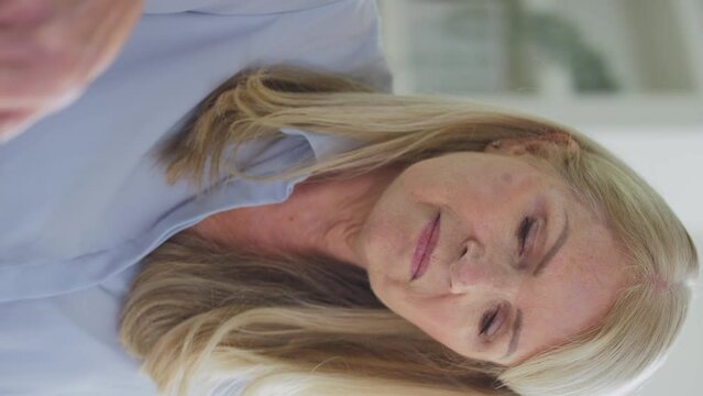 Vertical video of forgetful menopausal mature woman working on laptop suffering with poor memory shot in slow motion