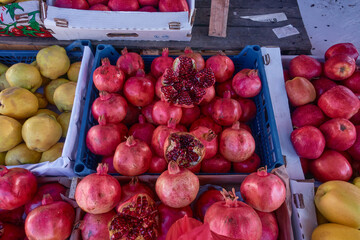 Pomegranate in boxes on the market. Fresh apples, pears, quinces and pomegranates are sold in plastic containers at the wholesale market. Selective focus.