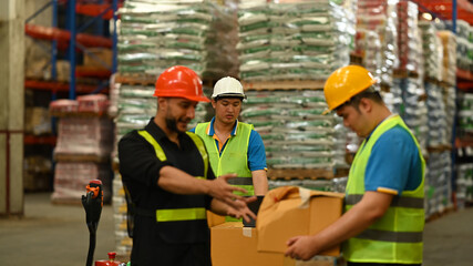 Warehouse workers working in the retail warehouse full of shelves with goods. Manufacture storehouse occupation concept