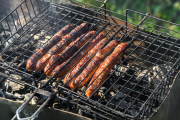 Frying sausages on the grill outdoors close-up. Grilled sausages,  B-B-Q