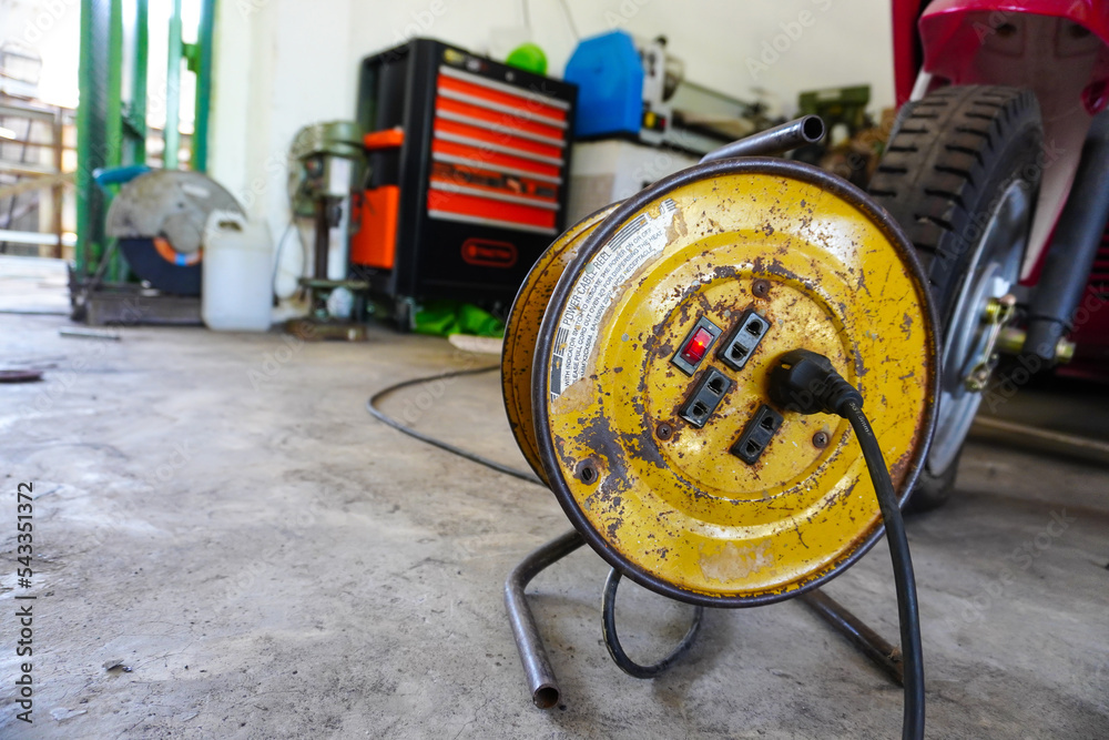 Wall mural rolled up red extension cord for electricity. cable reel in the workshop to supply power to electric