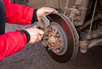 A man replaces the brake pads on a car. Security, service.