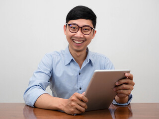 Positive businessman wear glasses holding tablet cheerful smile sit at the desk