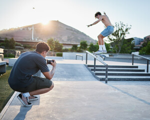 Skateboard jump outdoor, photographer in park for extreme sports photoshoot with skater in summer. Skatepark photo session, man grind rail and sport for fitness, stunt and training in Cape Town © Irshaad M/peopleimages.com