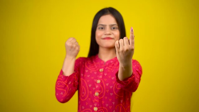 Young Indian girl showing finger after voting, cheerful girl isolated over yellow background