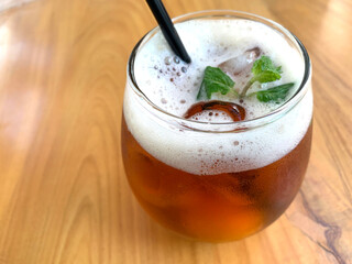 Sparkling citrus tea, organic tea with citrus and soda with hits of mint leaves in a Glass on top of wooden table