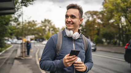 one young adult man student or tourist use mobile phone while wait bus