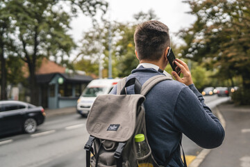 Naklejka premium one young adult man student or tourist use mobile phone while wait bus
