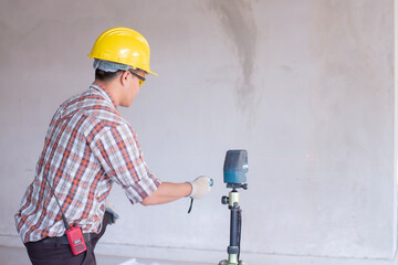 Worker in  measuring wall with laser leveler at construction site, Engineers at work checking construction building project with laser level machine during measurement work on site