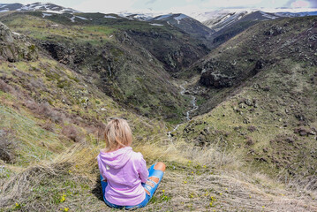 Naklejka premium A girl on mount Aragats near the 7th-century Amberd fortress, at the confluence of the Arkashen and Amberd rivers, Armenia.