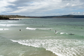 surfers enjoying good waves at Gwithian Beach in St. Ives Bay