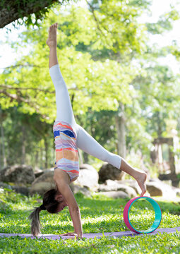 Young woman doing yoga exercises on the outdoor lawn.