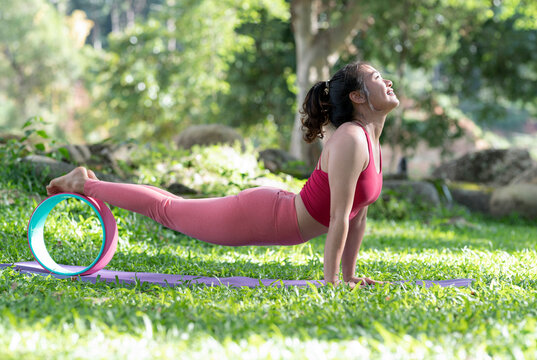 Young woman doing yoga exercises on the outdoor lawn.