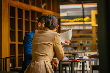 Two business friends working online in a cafe bar