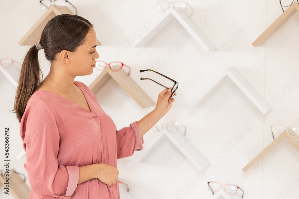 Poster Glasses, vision and retail with a woman customer looking at options in a optometry store while shopping for prescription lenses. Sale, eyewear and optometrist with a female consumer buying spectacles