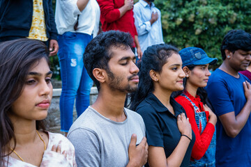 side view medium shot of group of spectators or audience praying or singing national anthem stadium before match - concept of respect, freedom and nationalism. - obrazy, fototapety, plakaty